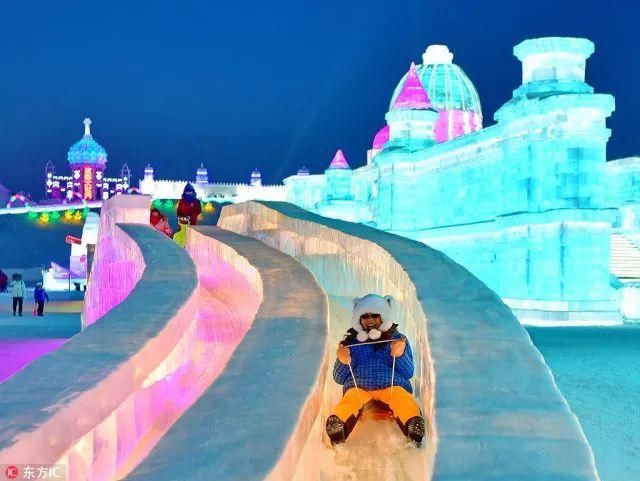游客在哈尔滨冰雪大世界玩冰滑梯.