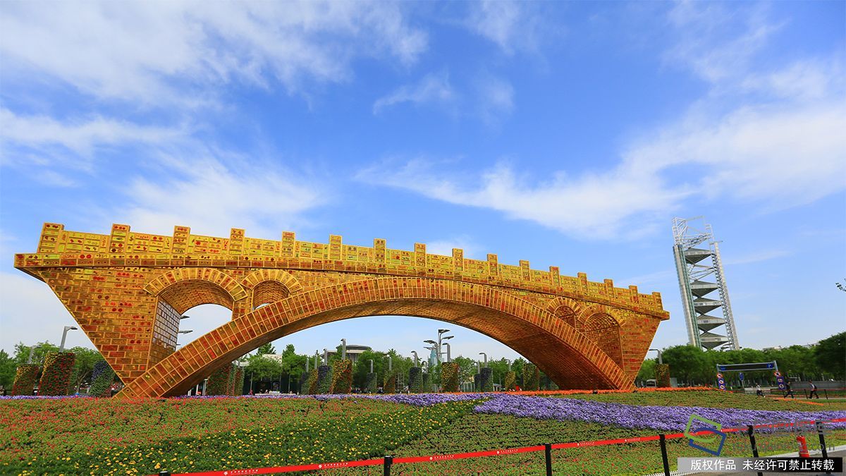 4月27日,在北京奥林匹克公园内拍摄的“丝路金桥”景观。据了解,“丝路金桥”景观作品主体结构模仿有1400多年历史、仍在使用的隋代建筑赵州桥,长28米、高6米、宽4米,由2万块“长城砖”形状的人造树脂水晶砖砌成,每块砖的内部熔铸丝绸制作的手工花,是陆上和海上“丝绸之路”沿线几十个国家、近百座城市的“国花”、“市花”,寓意架设“沟通之桥”。迎接即将在北京召开的“一带一路”国际合作高峰论坛(图片来源:tuku.qianlong.com)。千龙网记者 陈健男摄