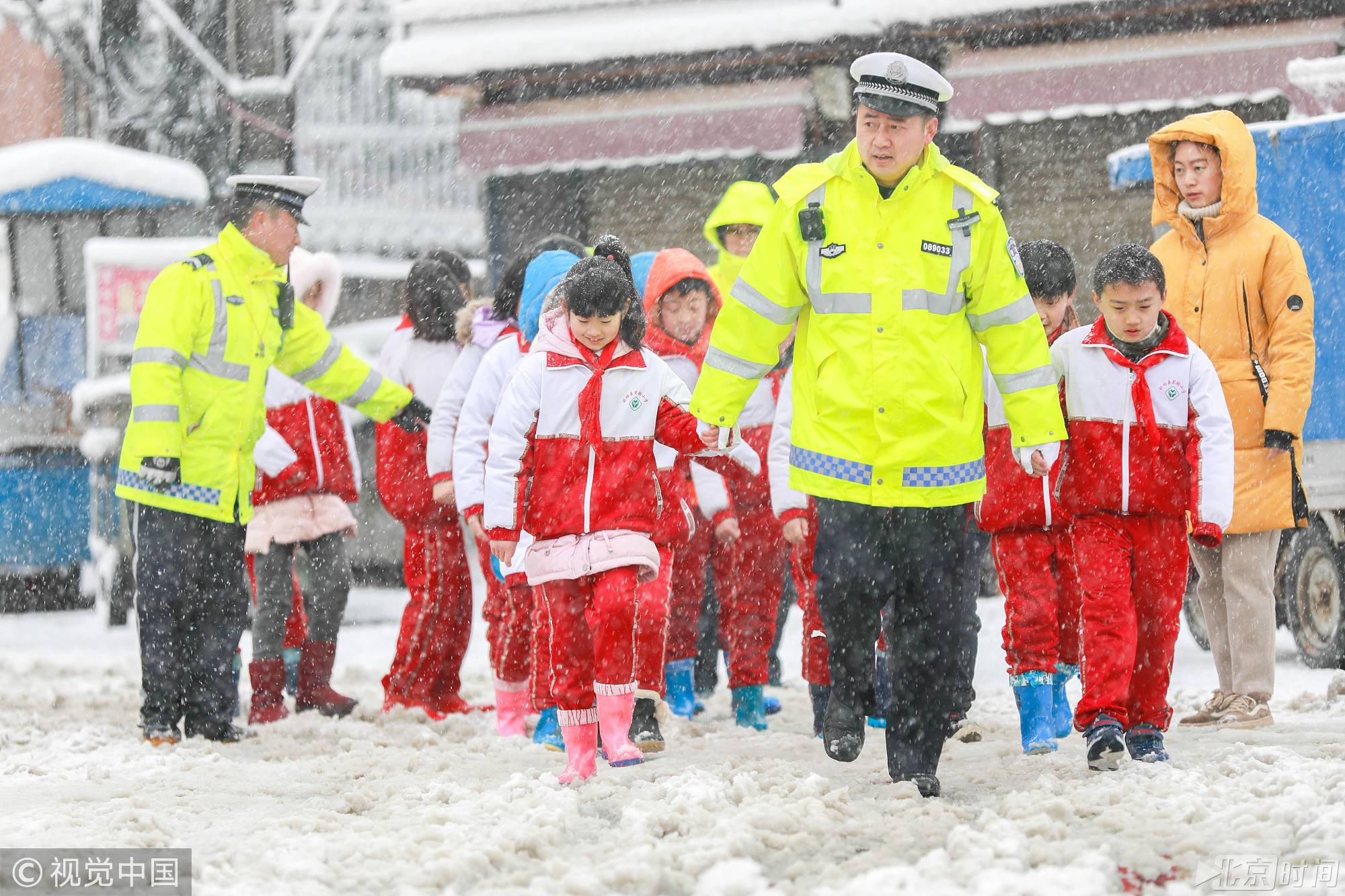 2018年1月4日，江苏淮安迎来暴雪天气，苏省气象局启动重大气象灾害（暴雪）Ⅳ级应急响应的命令，大雪还在持续，市民出行困难，交通警察在护送小学生过马路。图/视觉中国
