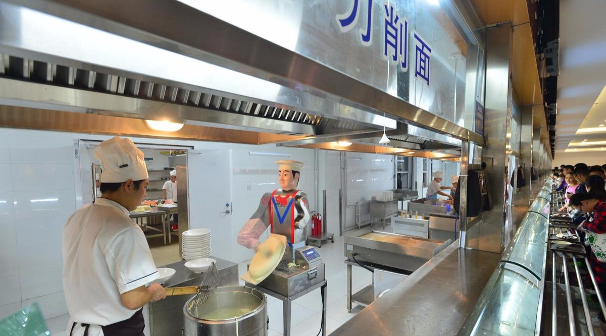 青岛一高校食堂，刀削面档口内一个刀削面机器人在制作刀削面。