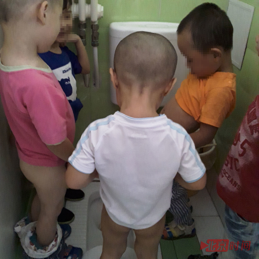 记者暗访期间，校区共有90名孩子，日常使用厕所坑位仅有两个。5、6个孩子同时在一个坑位便溺的情形时有发生，上厕所过程中也常有孩子把尿尿在其他孩子鞋上、裤子上。图为孩子们挤在一个隔间上厕所。