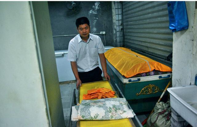 老房子里的太平间，因为下雨降温，没开空调。一走进去，冰棺运转散发的热气，立刻包围拢来，让人有些难受。