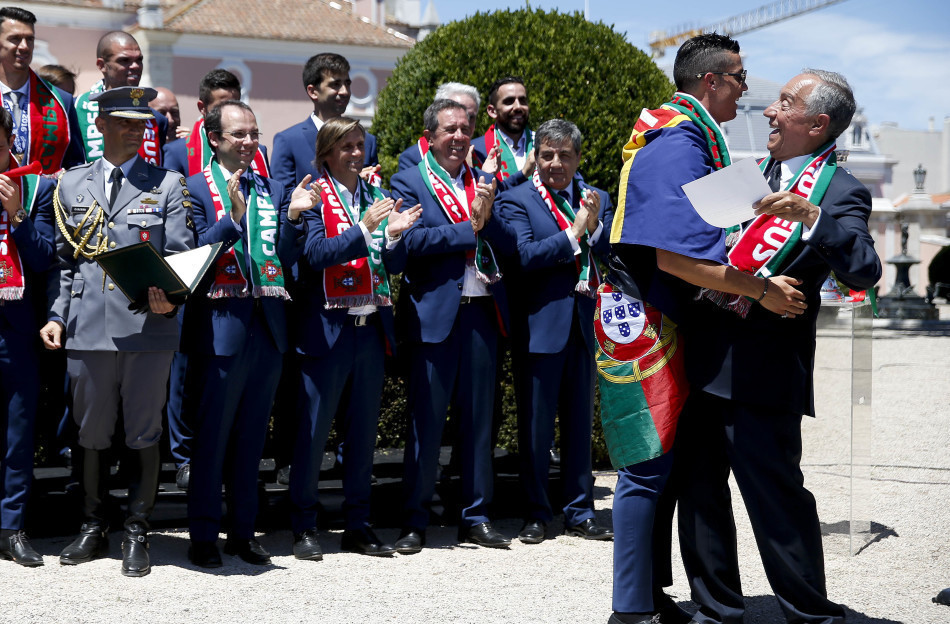 2016年7月11日，葡萄牙里斯本，2016年欧洲杯冠军葡萄牙队回到国内，全体队员和教练乘坐大巴游行并受到葡萄牙总统的接见，全城民众欢欣舞动狂欢庆祝。图为C罗拥抱总统