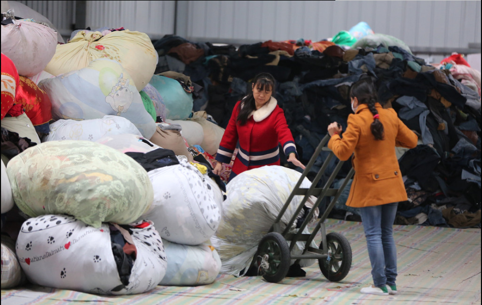 2016年10月13日，湖北省襄阳市，旧衣分拣中心里面堆放的旧衣物堆成了小山，工作人员根据衣服的成色、材质等进行分拣。