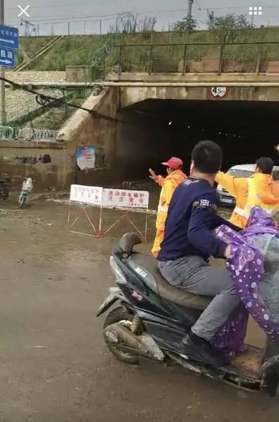 19日晚上，陈家四口开开心心去参加家庭聚会，夜深了，雨越来越大，就匆忙往回赶。夫妻二人各自骑着一辆电动车，一人带着一个孩子，老公陈开玉带着大女儿，老婆张春蕊带着小儿子。图为现场，隧道已经封锁，但依然有人想通过，协管员在艰难的劝阻，“不准过，不准过！”