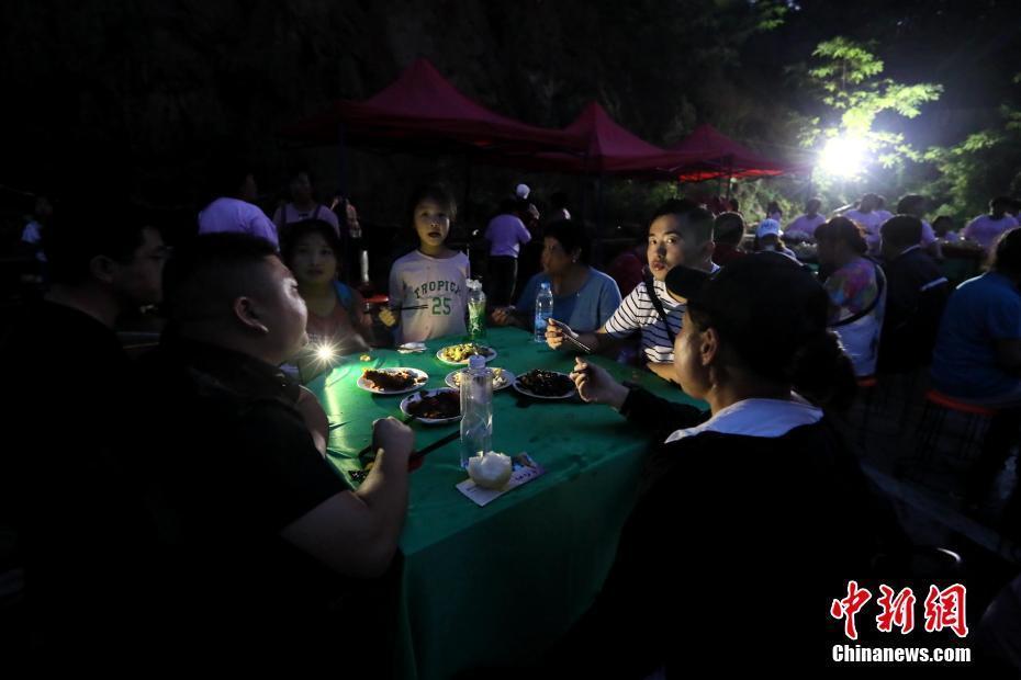 天色已晚，游客摸黑用手机灯光在桌子上寻找着美味。