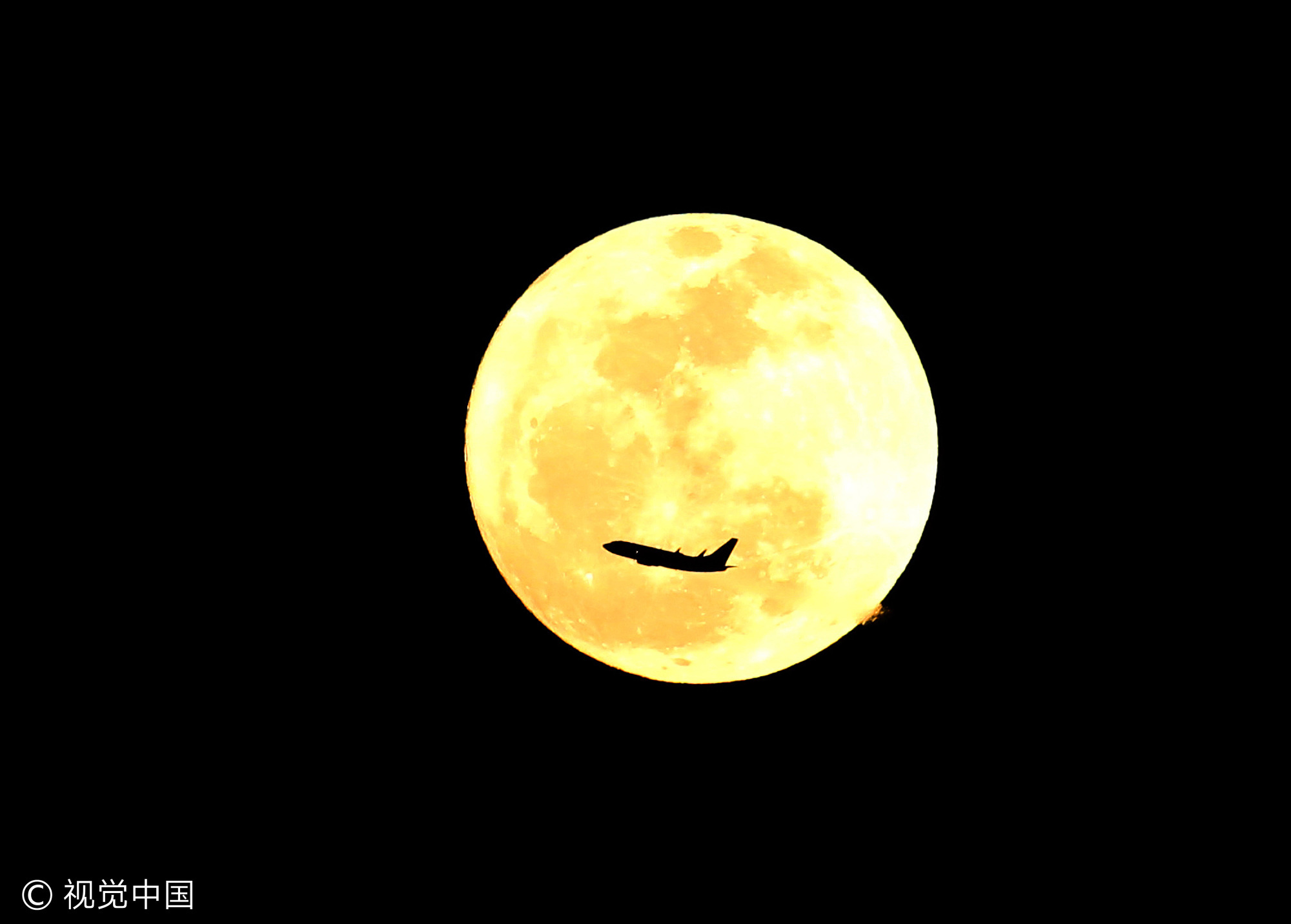 当地时间2013年1月26日,美国奥兰多国际机场,一架飞机起飞时刚好在一轮满月前“穿过”。