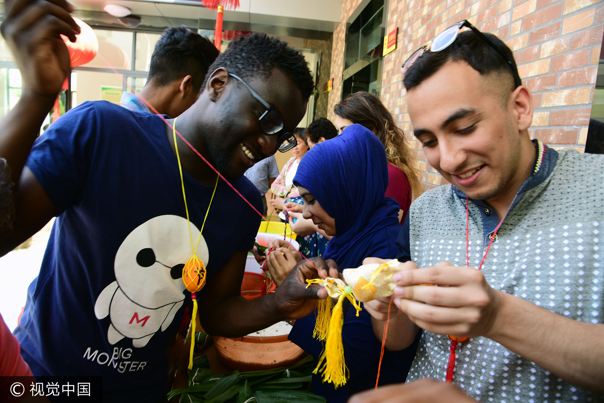 2017年5月25日,江苏镇江,社区居民在指导外国留学生包粽子。当日,端午节临近,江苏大学十多名来自赞比亚、印度、土耳其、巴基斯坦、南非等国的留学生走进镇江市和平路街道金江社区,在居民指导下学习包粽子、缝香囊,在咸鸭蛋上描画端午民俗,体验中国传统的端午文化。