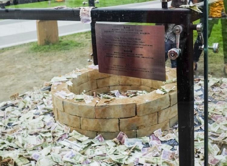 2017年10月12日，西安市刚开放的昆明池·七夕公园里，一个汉代陶井砖的玻璃展示柜里也被游客扔满了钱，其中甚至还有百元大钞。