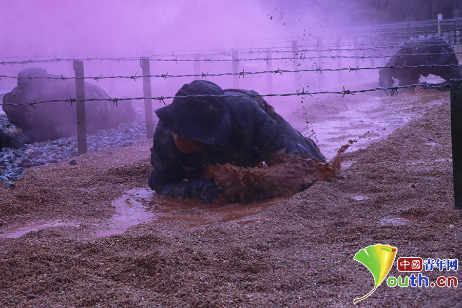 火箭军战士在低桩网下匍匐前进,大雨滂沱,泥花飞溅。 中国青年网记者 卢冠琼 摄