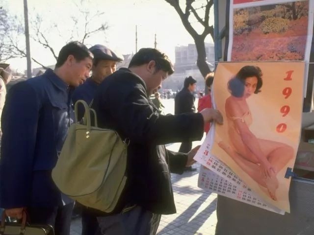 1990年的街头挂历市场，几位大叔正在翻看。