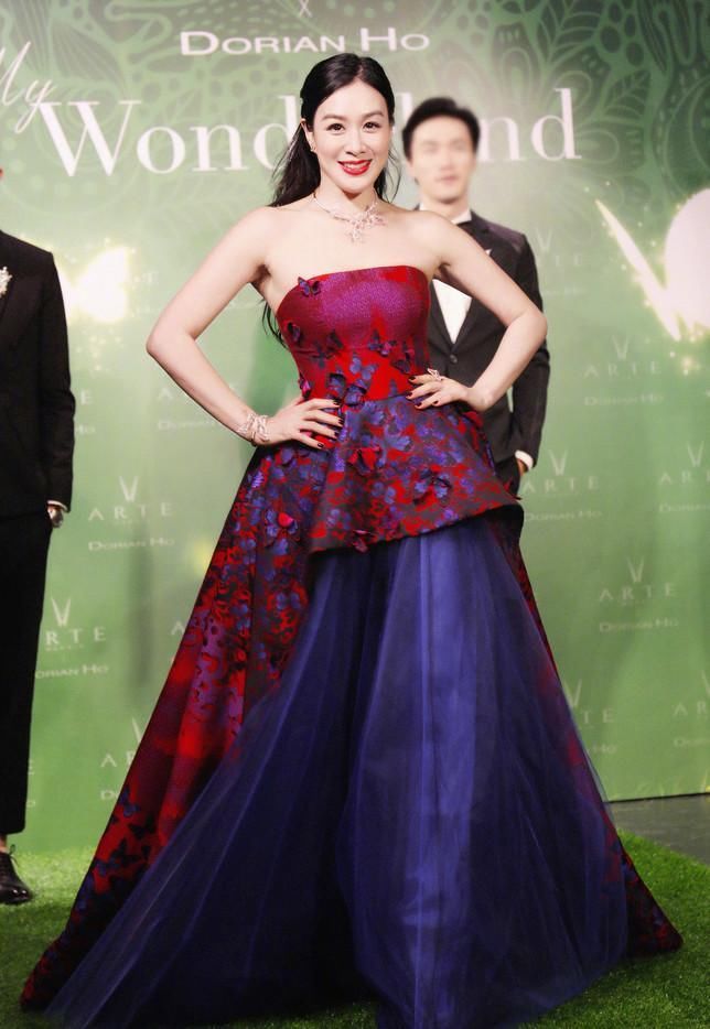 钟丽缇身穿一件抹胸礼服,姿态优雅,红色的装饰和紫色的底色相映衬