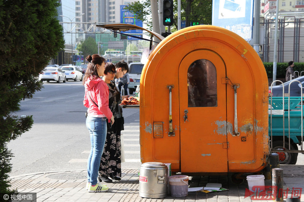 2009年，北京市又搞早餐示范工程招标，要求企业有独立加工、配送中心。2016年4月10日，北京朝阳区西大望路，马路边人行便道上在早餐车前买早点的上班族。