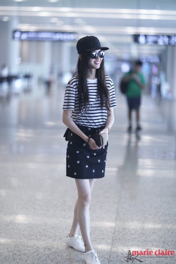 唐嫣现身机场。她头戴MLB黑色棒球帽，戴黑色猫眼墨镜，身穿白色条纹圆领T恤，肩背Louis Vuitton黑色链条包，下穿黑色星星刺绣半身裙，脚踩白色系带休闲鞋。