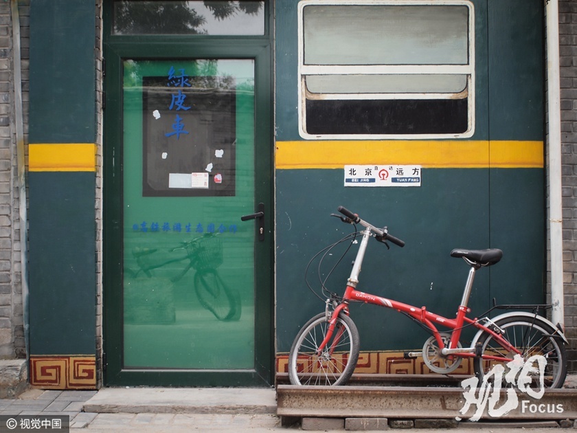 想必这家主人是个火车迷，自己的房子都涂成绿皮车的模样，而火车的轮子就在门前。