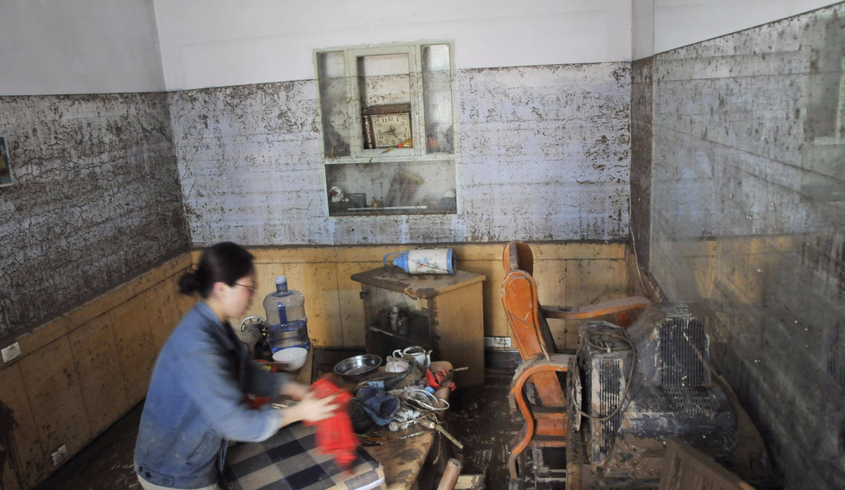 7月23日，井陉县小作镇南石门村村民在清理住房。从墙上留存的痕迹可以看出，当时冲进屋里的水大约有两米多高。从19日13时到20日8时，井陉县遭受特大暴雨袭击，平均雨量高达545.4毫米，局部区域达到688.2毫米，一天降雨就超出井陉县2015年全年降雨量。新华社记者 巩志宏 摄