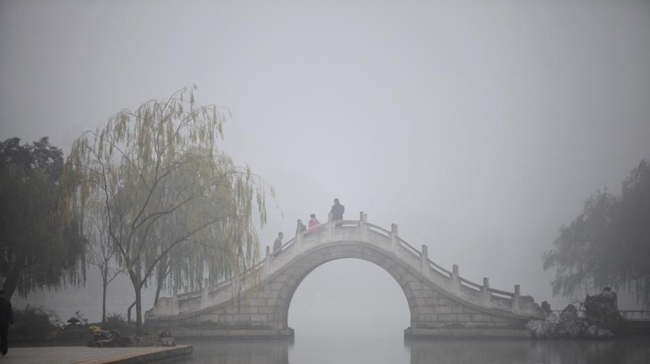 11月26日，古城扬州大雾弥漫，雾中的瘦西湖风景区云雾缭绕，吸引了一批中外摄影爱好者和游人前来采风、游览。图为一批摄影爱好者和游人雾中游瘦西湖。