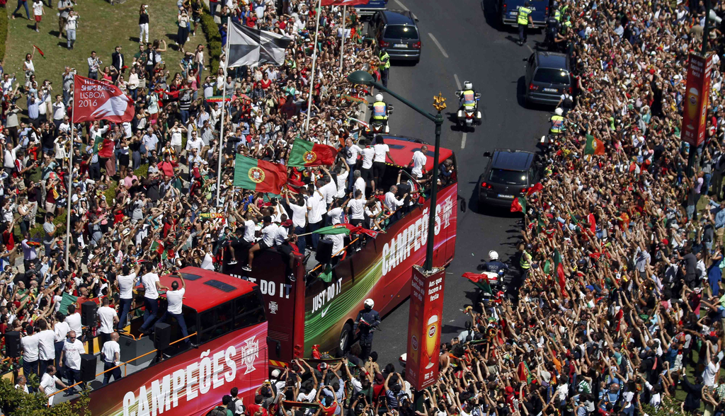 2016年7月11日，葡萄牙里斯本，2016年欧洲杯冠军葡萄牙队回到国内，全体队员和教练乘坐大巴游行并受到葡萄牙总统的接见，全城民众欢欣舞动狂欢庆祝。图为巡游大巴收到葡萄牙民众热情迎接