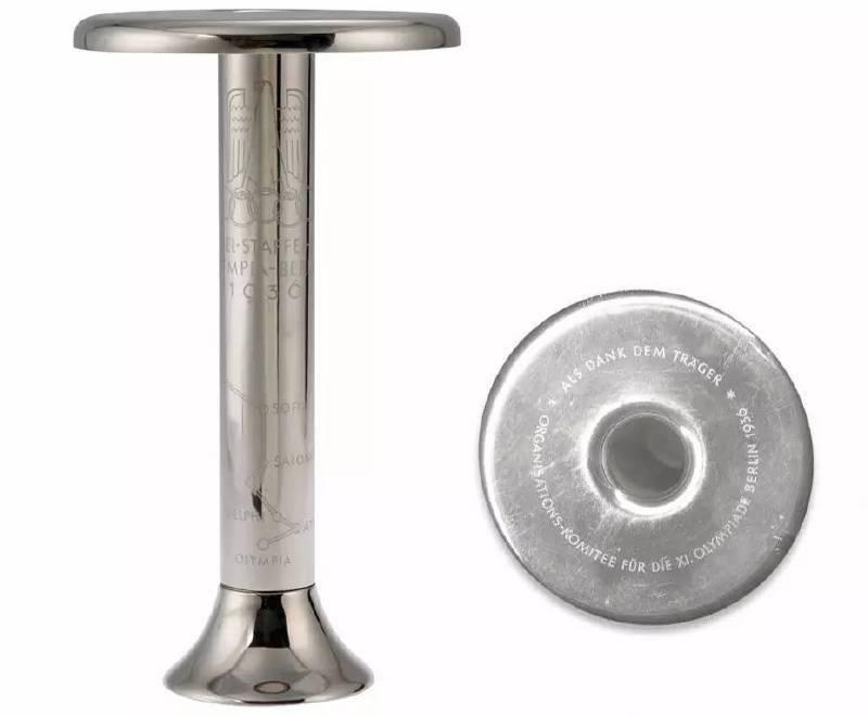 由经抛光处理的钢材料制成，在手柄部分刻有“Fackelstaffel-LaufOlympia-Berlin 1936（奥林匹亚火炬接力-柏林 1936）”，字体上方还有奥林匹克五环和德国的鹰徽标志，字体下方绘有本次火炬传递的路线图，在火炬体顶部的平台上则写有感谢火炬手的字样。