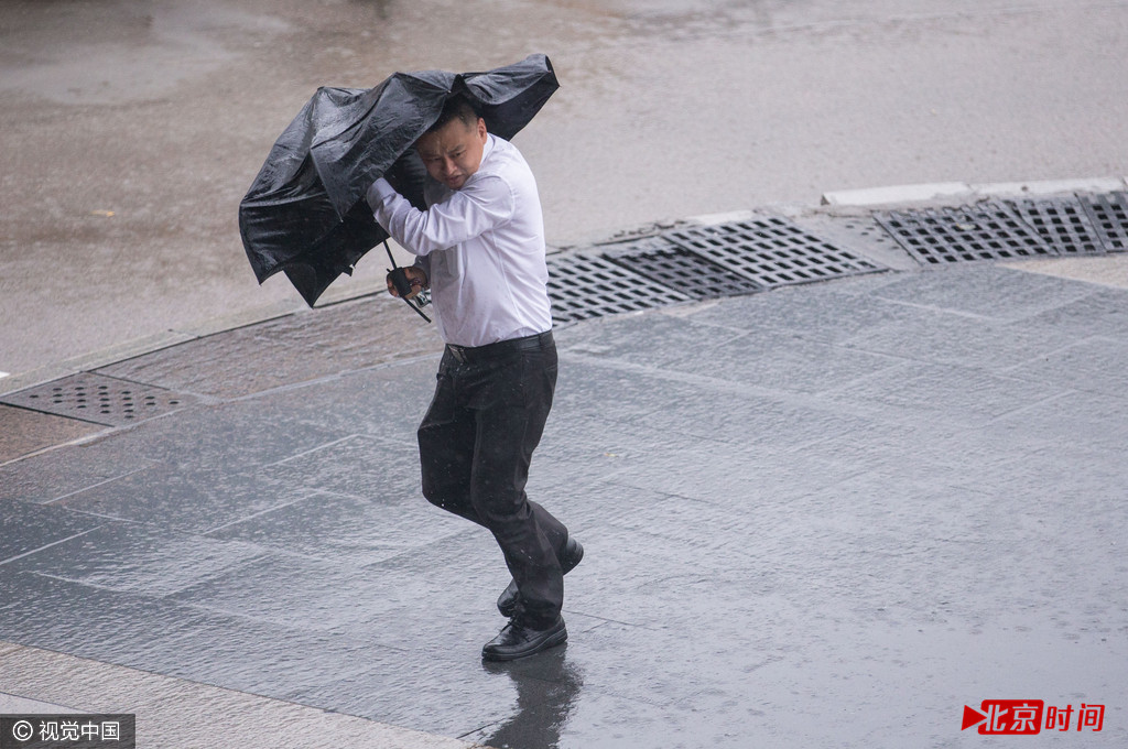 强风把市民雨伞都吹变形了。