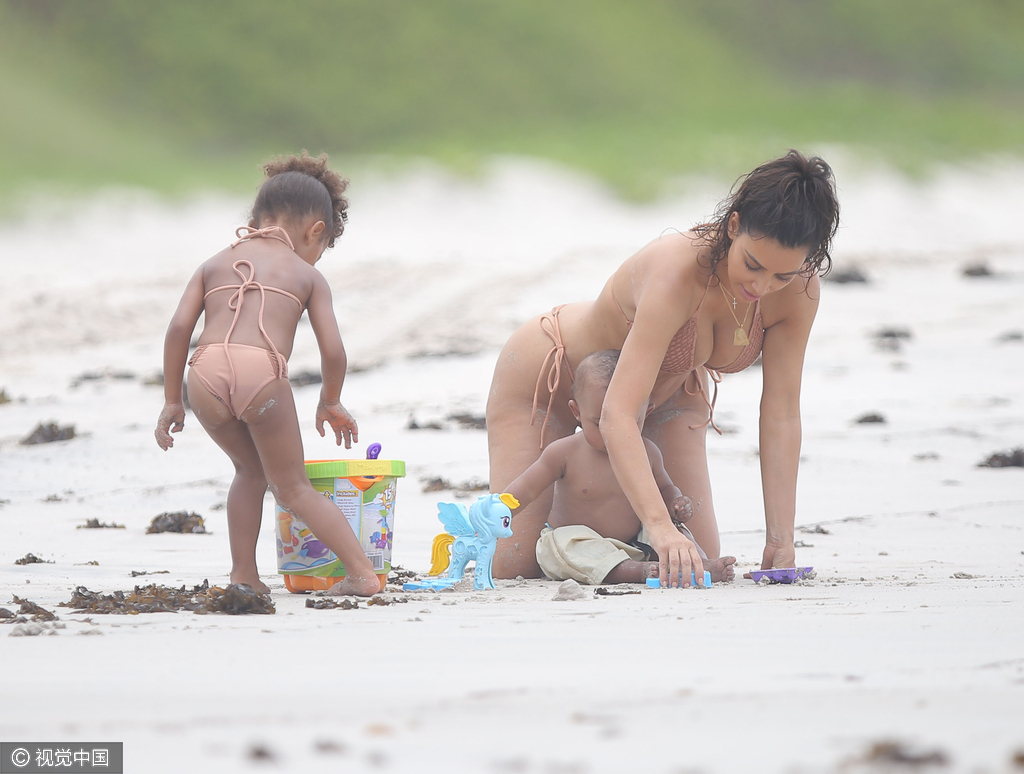 当地时间8月18日，金·卡戴珊（Kim Kardashian）带女儿小西北和儿子沙滩玩耍，卡戴珊身穿裸色系带比基尼，女儿与妈妈同款可爱十足，在沙滩上卡戴珊全程呵护幼子母爱爆棚，然而抢镜的还是翘臀。图为卡戴珊教幼子玩游戏。