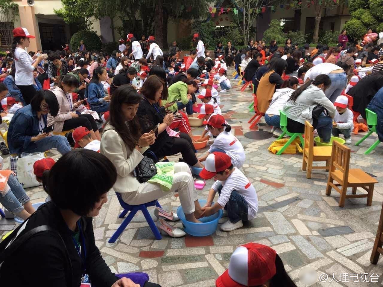 幼儿园孩子为母亲洗脚 妈妈们却只顾低头玩手机